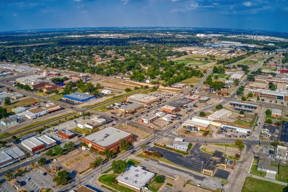Aerial view of downtown Mesquite, Texas, showcasing commercial buildings, streets, and surrounding neighborhoods on a clear sunny day