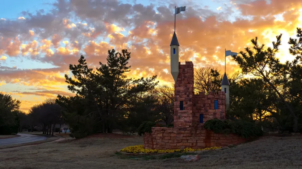 Scenic view of Wichita Falls, Texas at sunset with a small castle-like stone structure and vibrant sky in the background.
