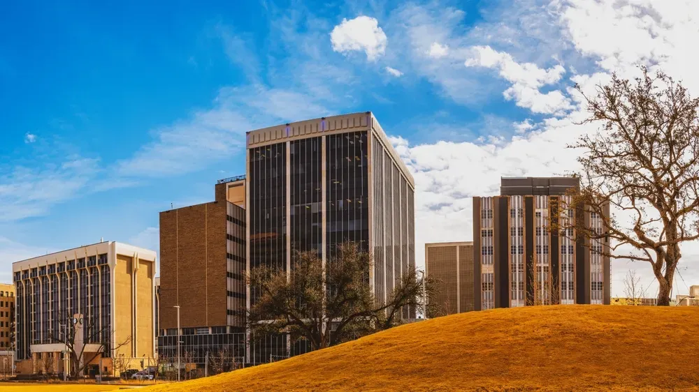 Modern office buildings in downtown Midland, Texas, under a vibrant blue sky.