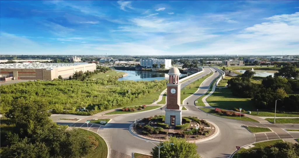 Scenic aerial view of Cedar Park, Texas with a prominent clock tower roundabout and commercial buildings, promoting digital marketing services in the area.