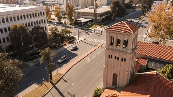 Aerial view of downtown Bakersfield, California, showcasing a historic clock tower, tree-lined streets, and surrounding city buildings.