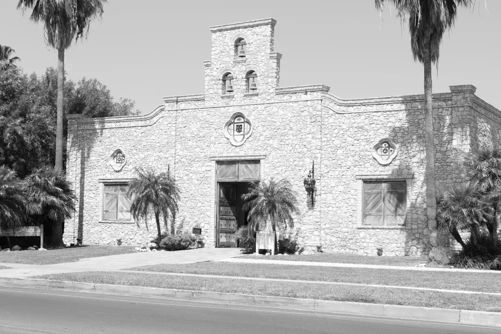 Historic stone building with palm trees and arched entrance in McAllen, Texas