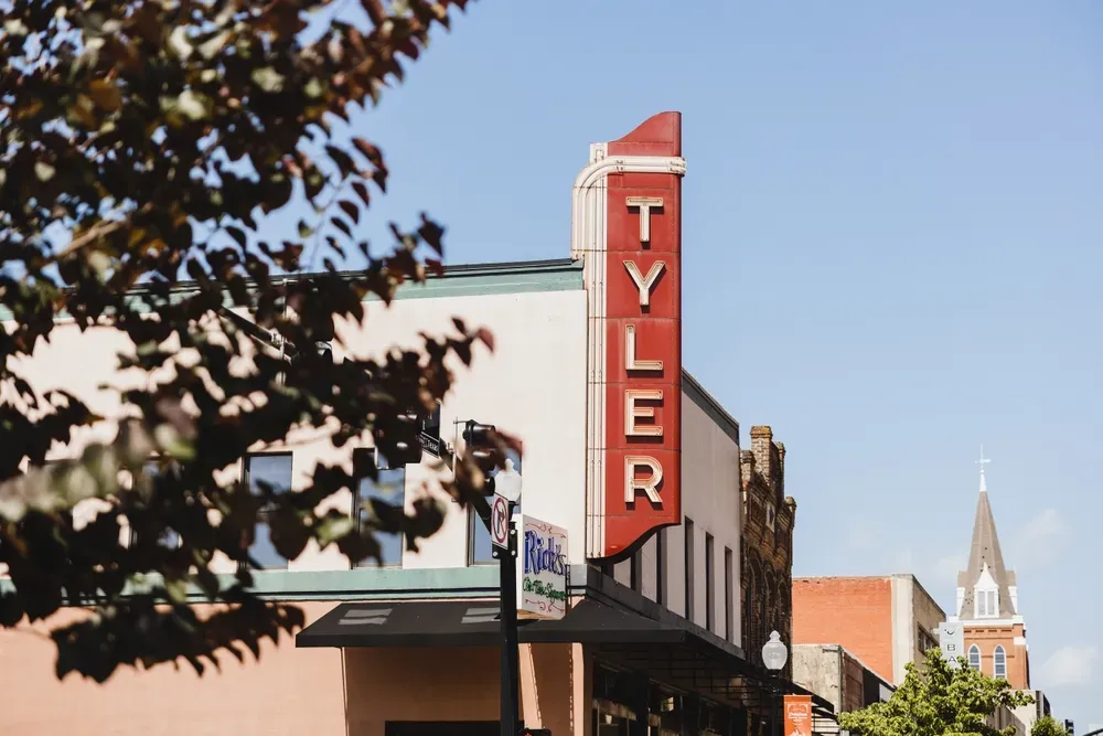 Downtown Tyler, Texas with historic Tyler theater sign and nearby buildings under a clear blue sky.