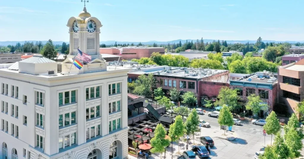 Aerial view of downtown Santa Rosa, CA featuring the historic clock tower and surrounding shops and trees on a sunny day.