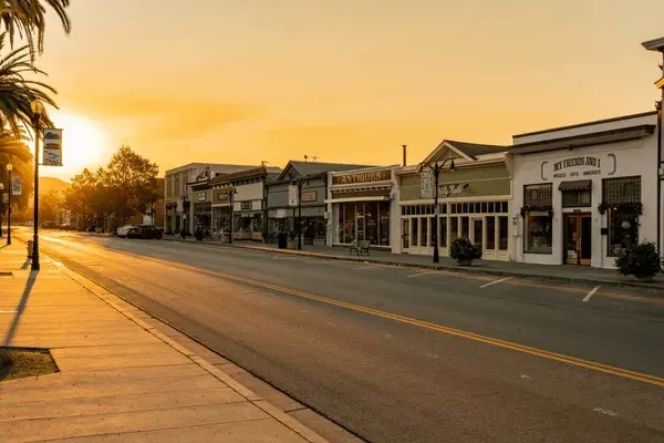 Historic small-town street in Fremont, CA at sunset, lined with boutique shops and palm trees