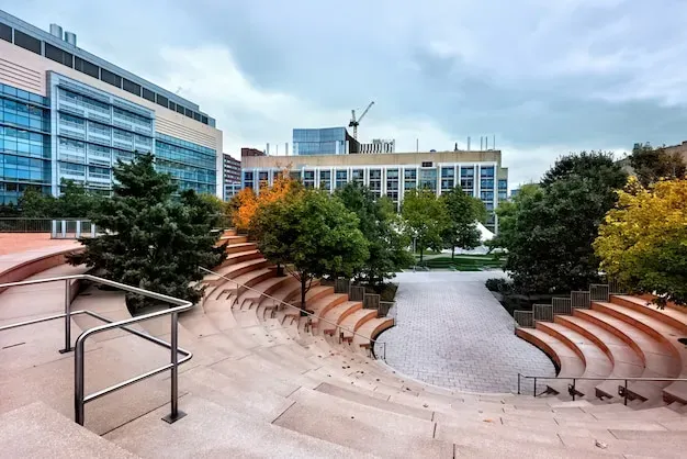 Modern outdoor amphitheater with tiered seating surrounded by trees and contemporary buildings in College Station, Texas.