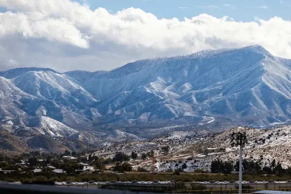 Snow-covered mountains near Santa Clarita, California, with scattered homes and clear skies in the background.